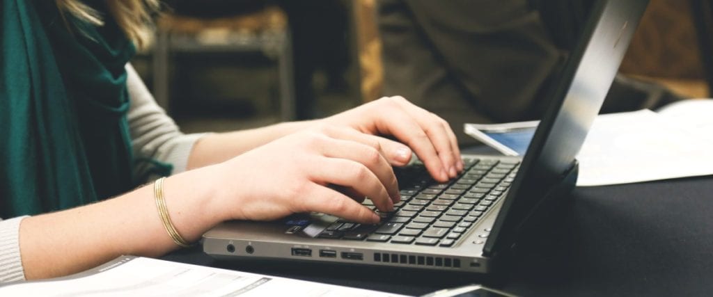 hands typing on a laptop keyboard