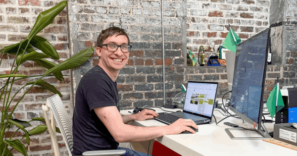 Flynn looks up from his laptop and smiles at the camera.