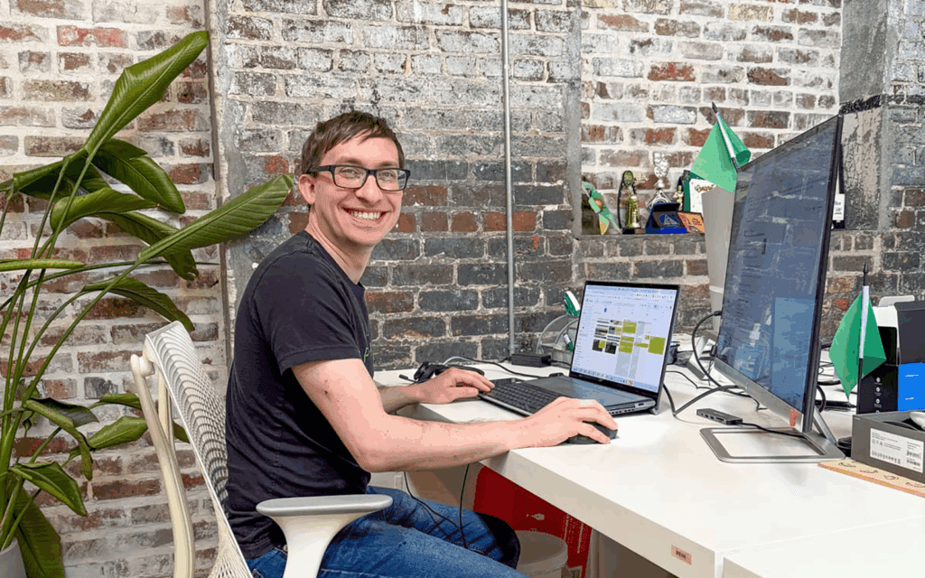 Flynn looks up from his laptop and smiles at the camera.