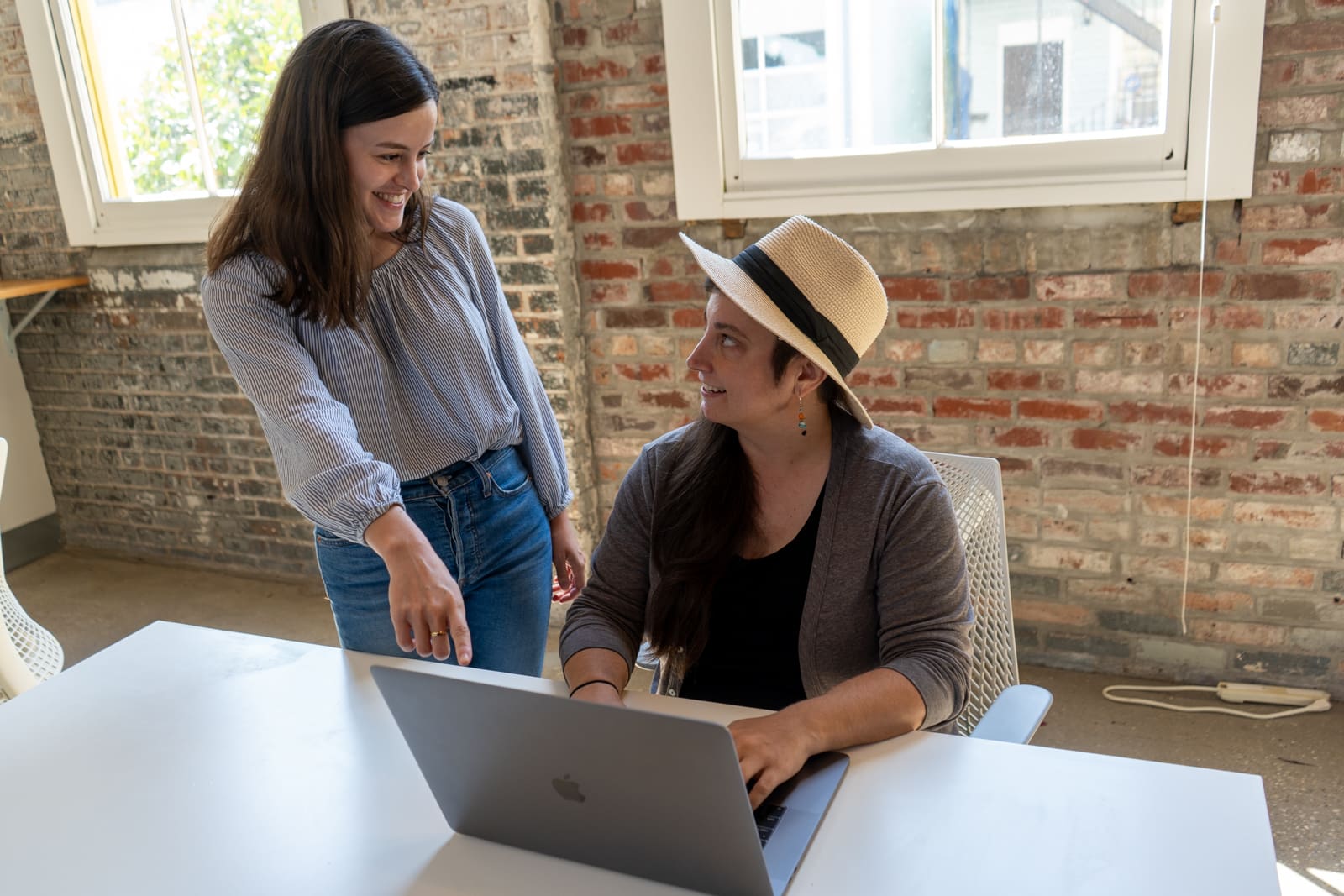 Claire points to something on Amanda's laptop and both smile.