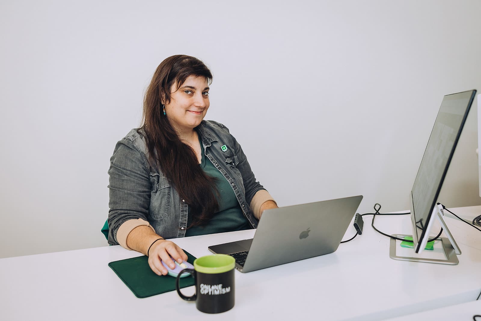Amanda smiles at the camera at her desk in the Online Optimism office.
