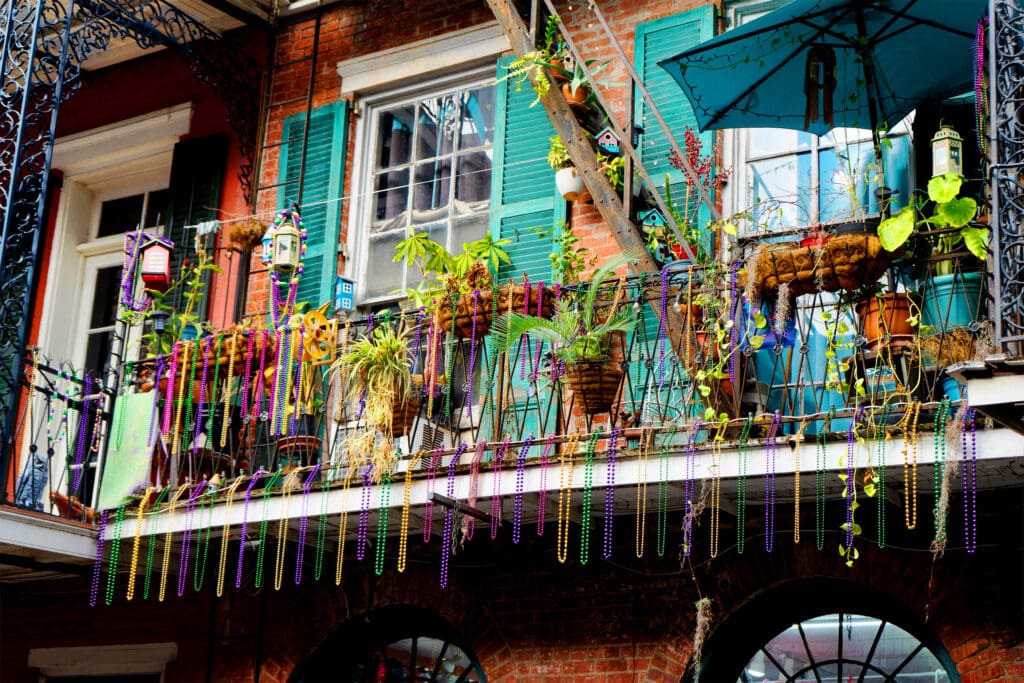 Mardi Gras beads hang from a colorful balcony in New Orleans.