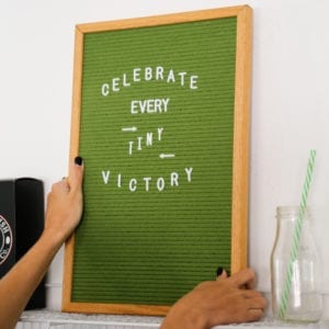 Green letterboard reading "Celebrate every tiny victory."