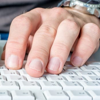 Hands typing on a computer keyboard.