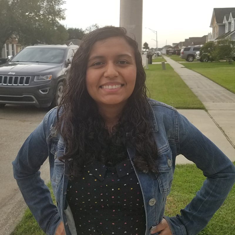 Person posing outside for a headshot with busy background