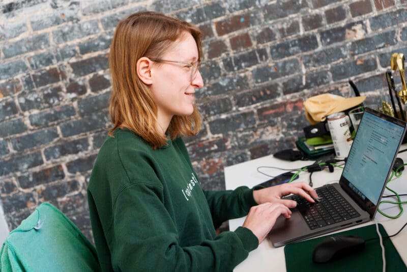 Lauren smiles at her laptop as she creates a new content document.