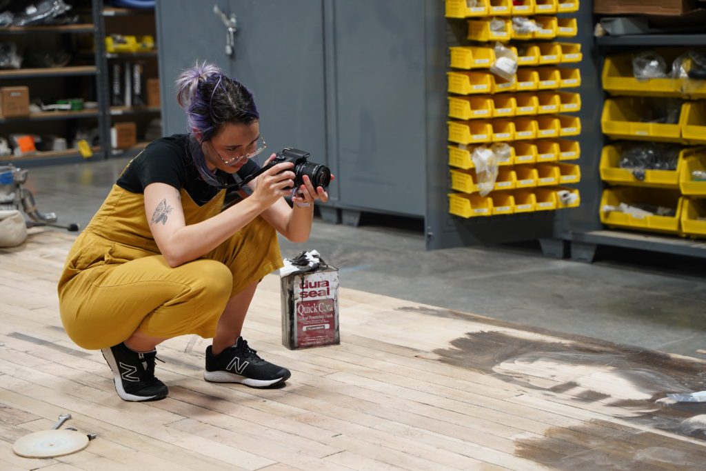 Optimist crouching to take photos with a camera