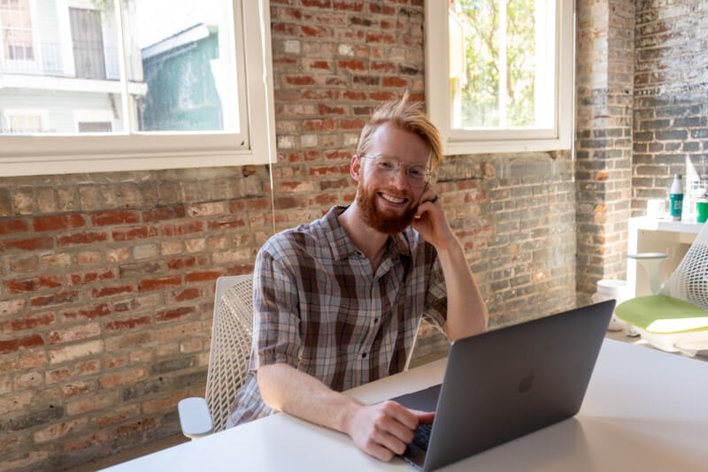 Alex looks of from a laptop and smiles.