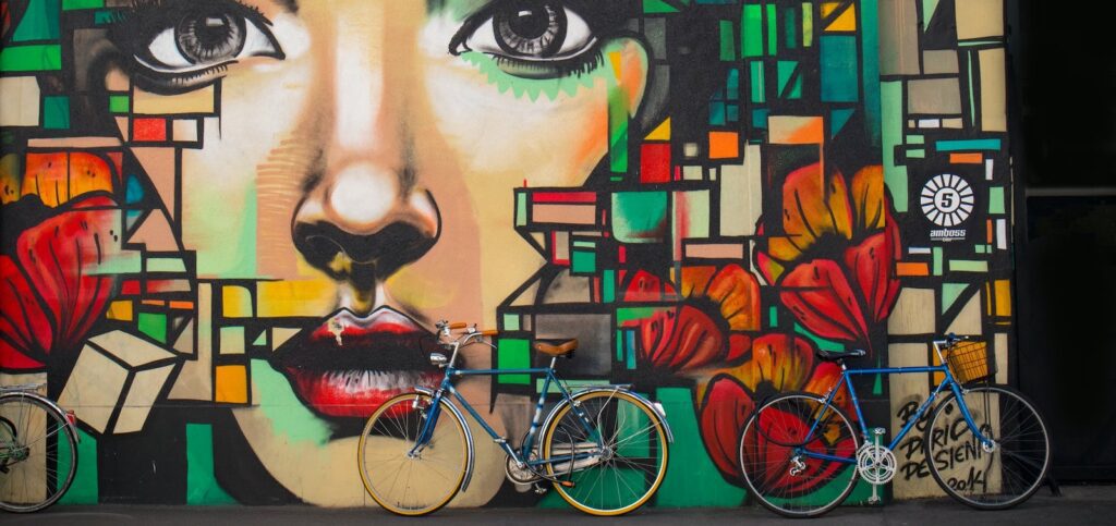 A mural of a woman's face surrounded by geometric patterns in tones of green and orange