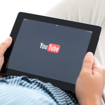 A person holding a tablet with the YouTube loading screen