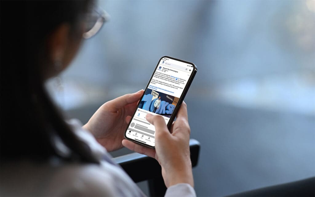 Business woman looks at a LinkedIn post from Square Peg Technologies on her phone