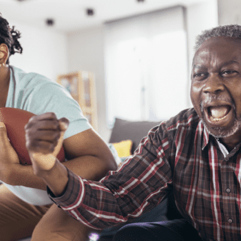 A father and son yelling enthusiastically while watching the football game, demonstrating the importance of having a winning 2025 Super Bowl marketing strategy