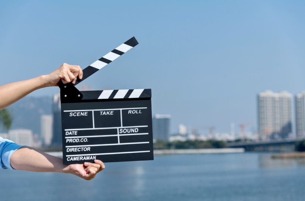 Woman hands holding film slate by the sea.