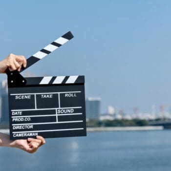 Woman hands holding film slate by the sea.