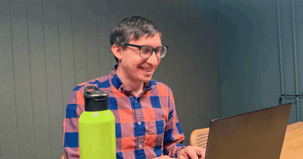 Flynn smiling with Reddit water bottle and laptop.