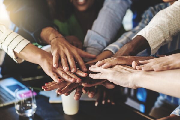 A group of people put their hands together in a circle over a table.