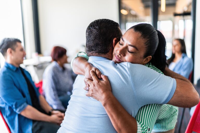 Mature couple embraced after talking in a group therapy at mental health center