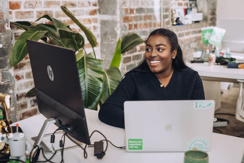 Alyssa sits at her desk in the Online Optimism office, smiling at the computer.