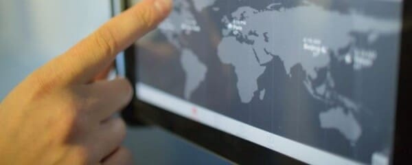 A person swiping on a world map on a tablet screen.