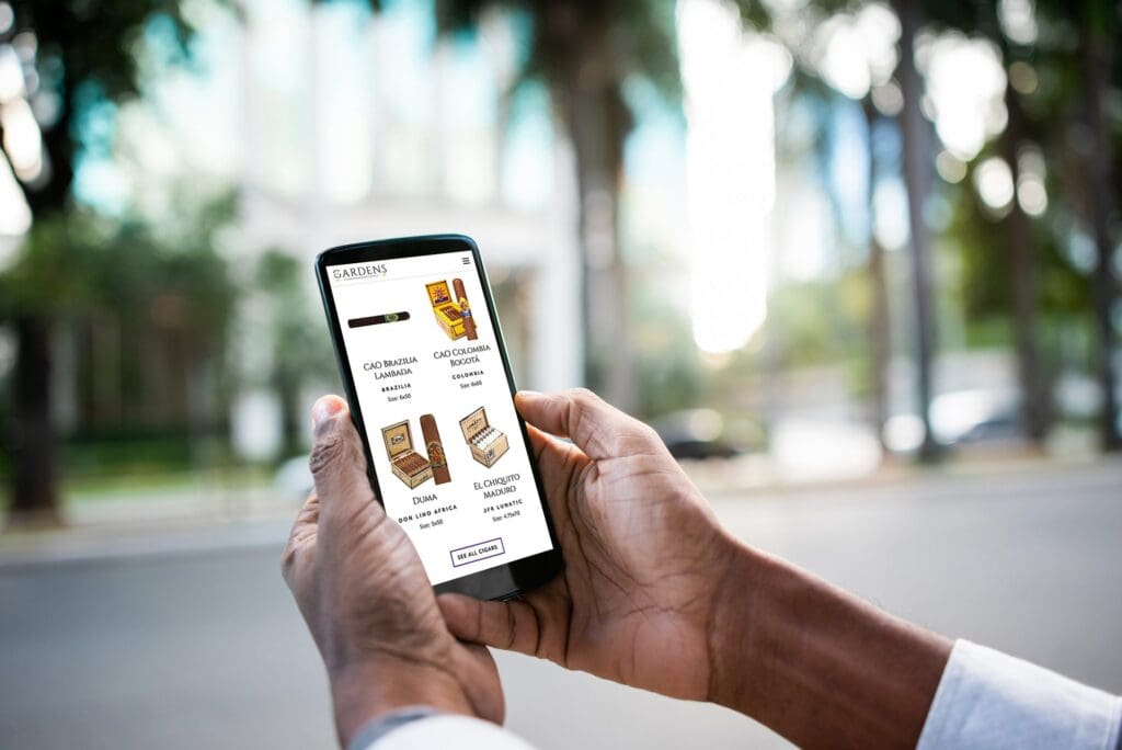 Man uses The Gardens Cigar and Whiskey Lounge's website to see cigar listings on his phone