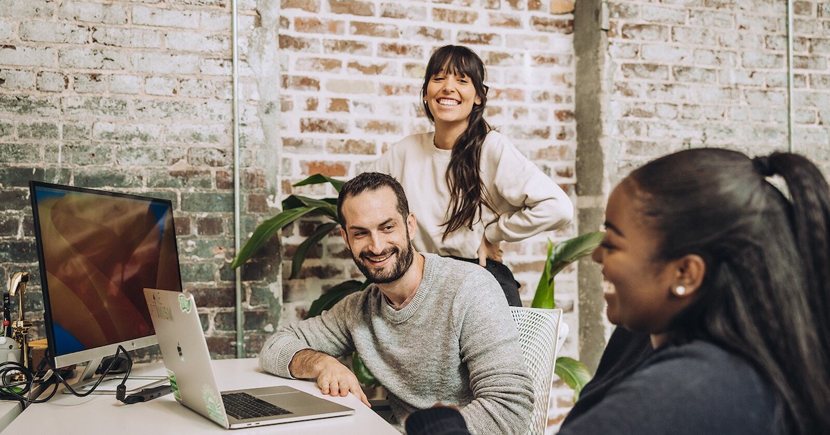 Sam, Jordan, and Alyssa talking and contributing to the work culture in our advertising agency