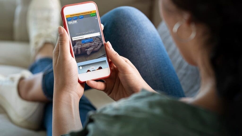 Teenager uses VIA LINK's new website on a phone sitting on a couch