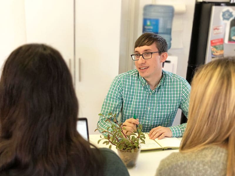 Flynn meets with two employees at a table in the office.