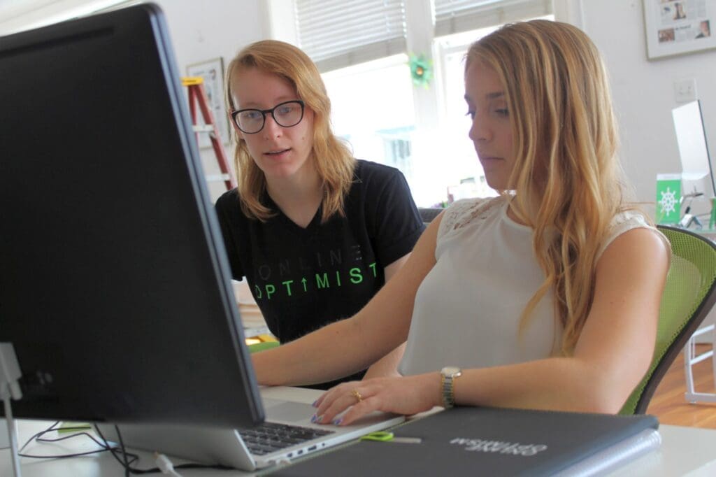 Lauren reviews a Content Specialist's work at the Online Optimism office.