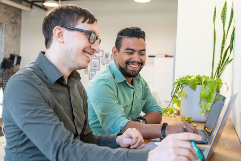 Flynn and Esteban look at a laptop together.