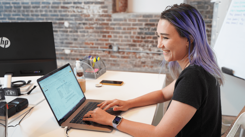 Meara smiles at her laptop while preparing a presentation.