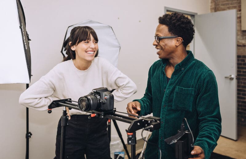 Jordan and Daniel laugh together as they set up a camera on a sliding tripod.