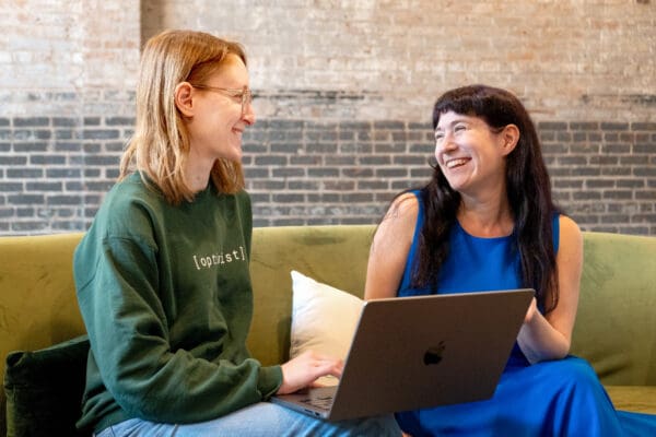 Lauren, our Director of Search and Content, and Simone, our Spring 2025 Content Specialist, smile as they look at a laptop screen.