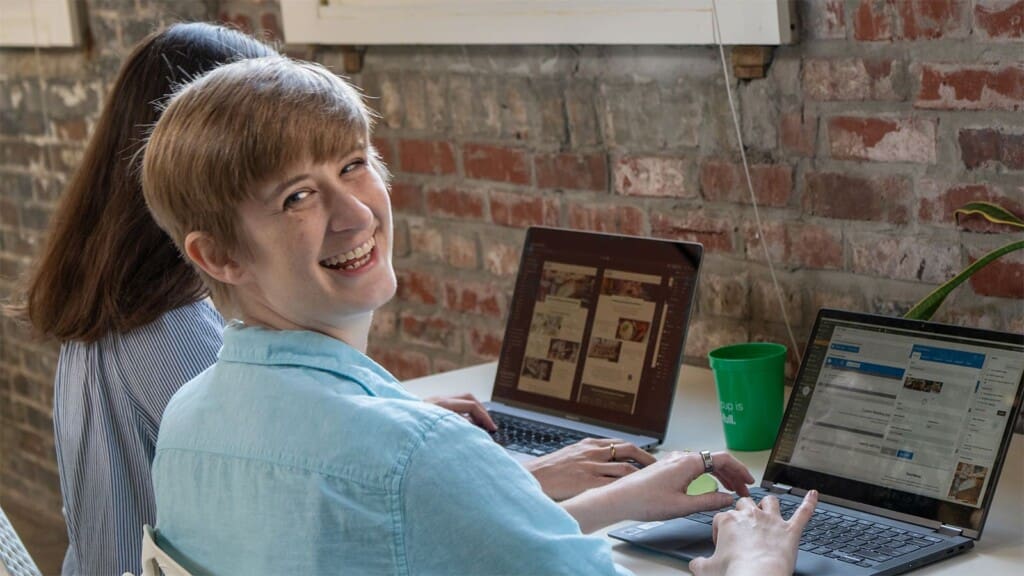 Ivey glances back at the camera with a smile, working beside Claire at the Online Optimism office.