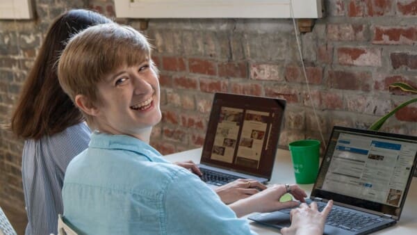 Ivey glances back at the camera with a smile, working beside Claire at the Online Optimism office.