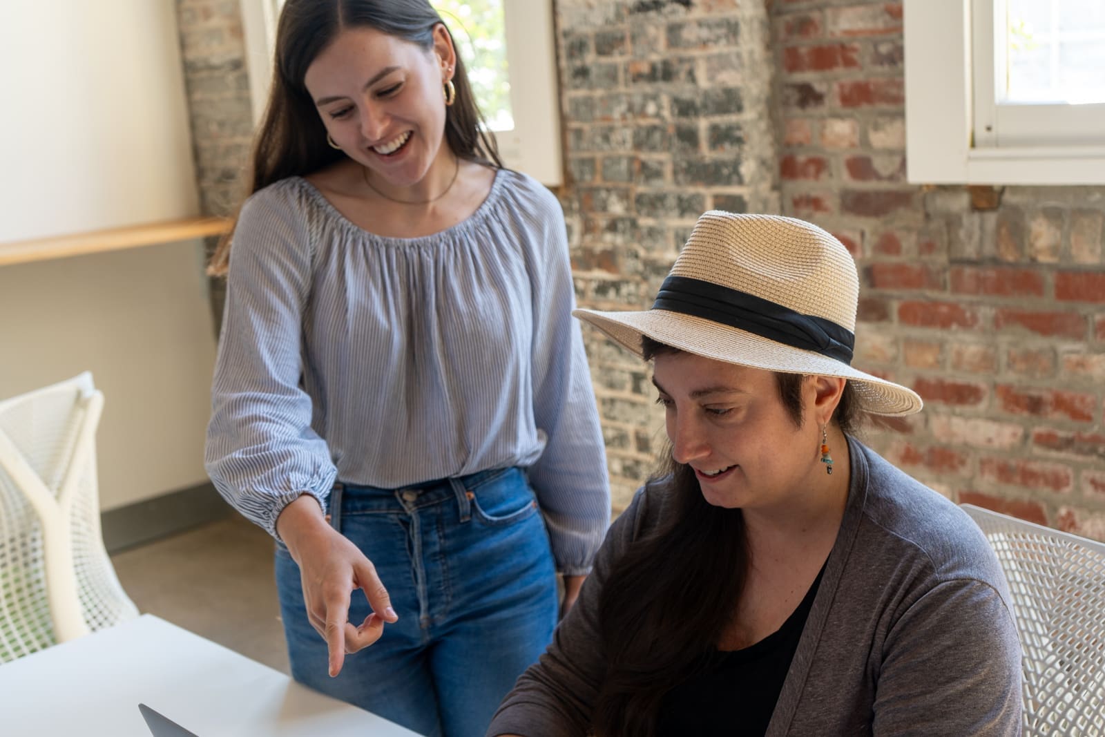 Claire indicates something to Amanda, and both smile at it.