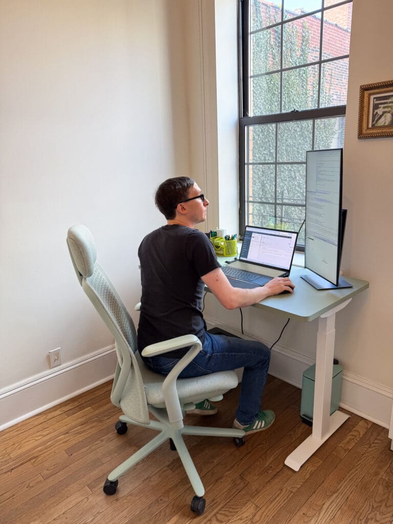 Flynn works from home, looking between his laptop and a vertical monitor.