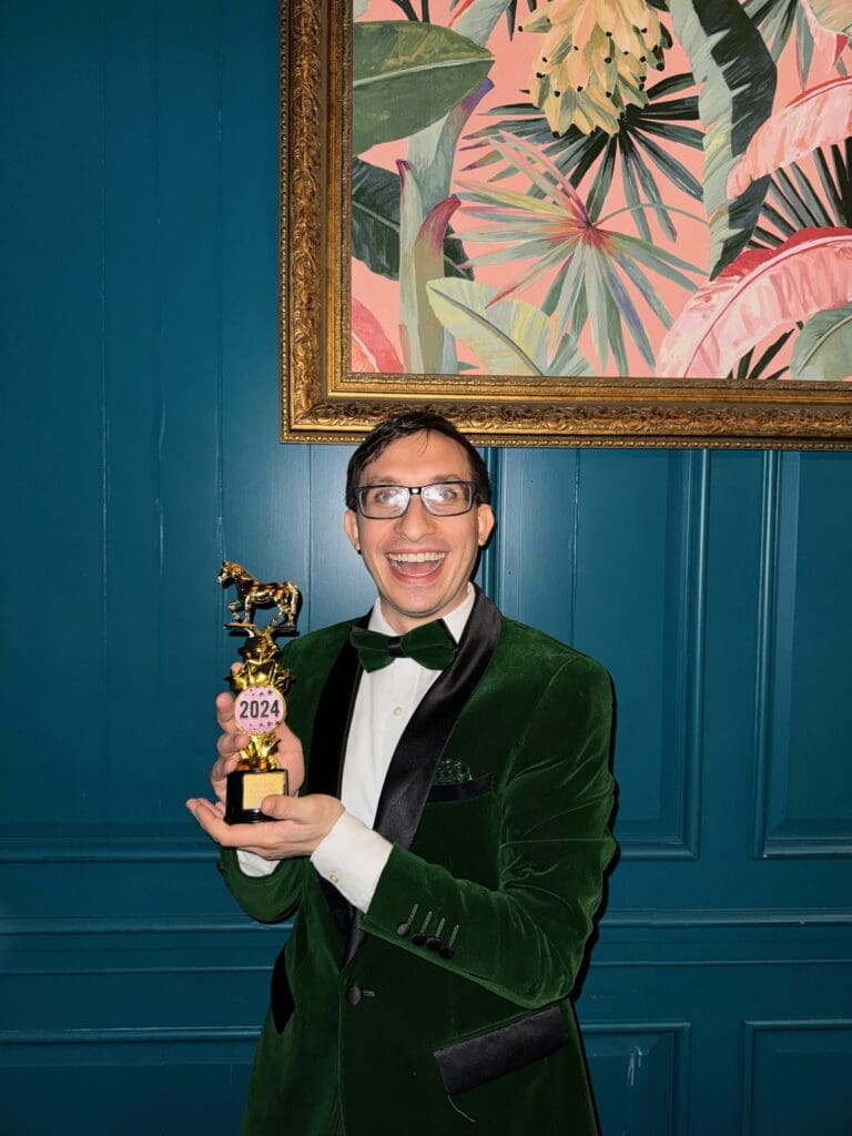 Flynn holds up his 2024 OOie Award trophy with a smile.