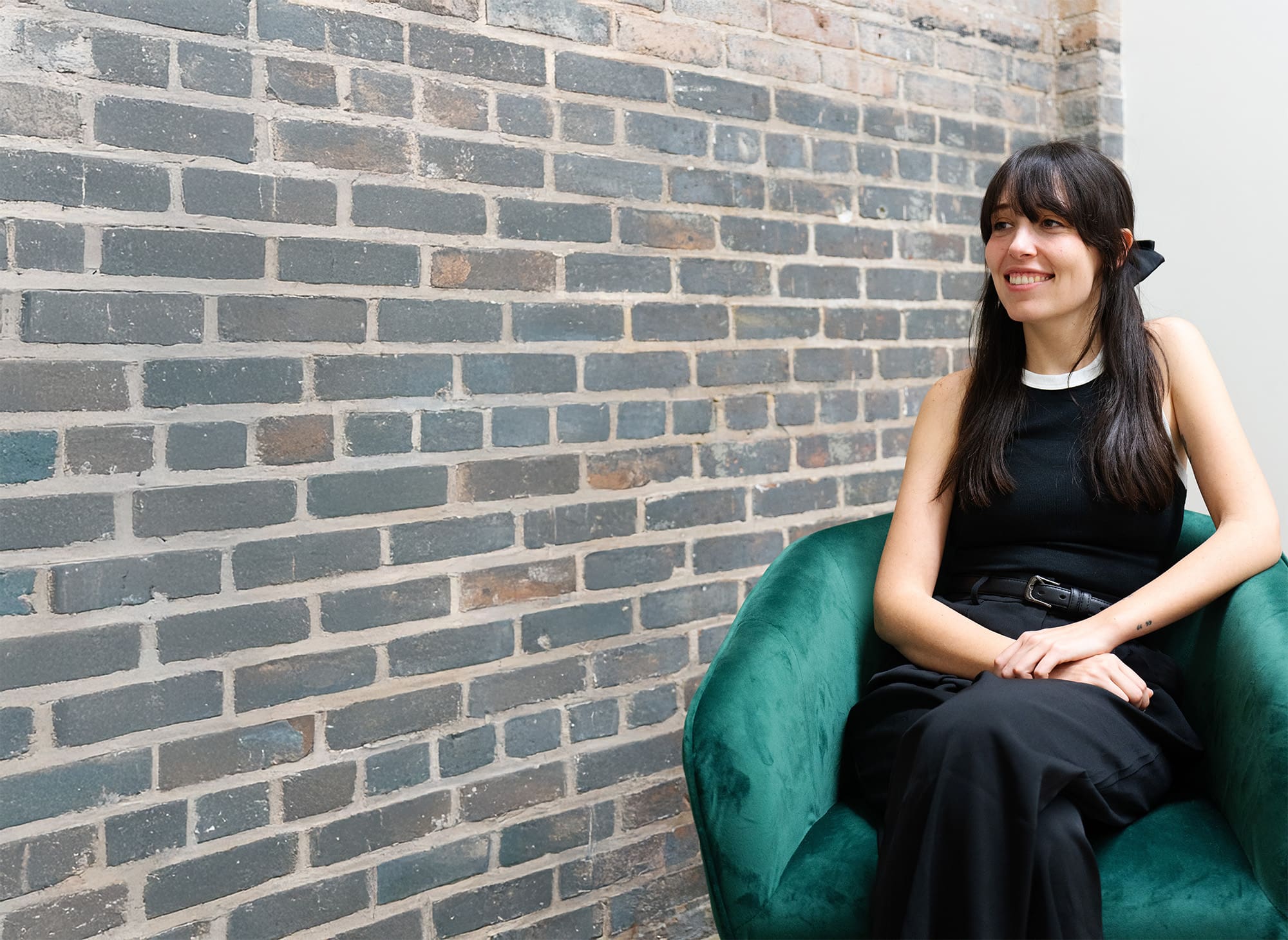 Jordan sits in a green chair at the Online Optimism office, listening to someone out of frame.
