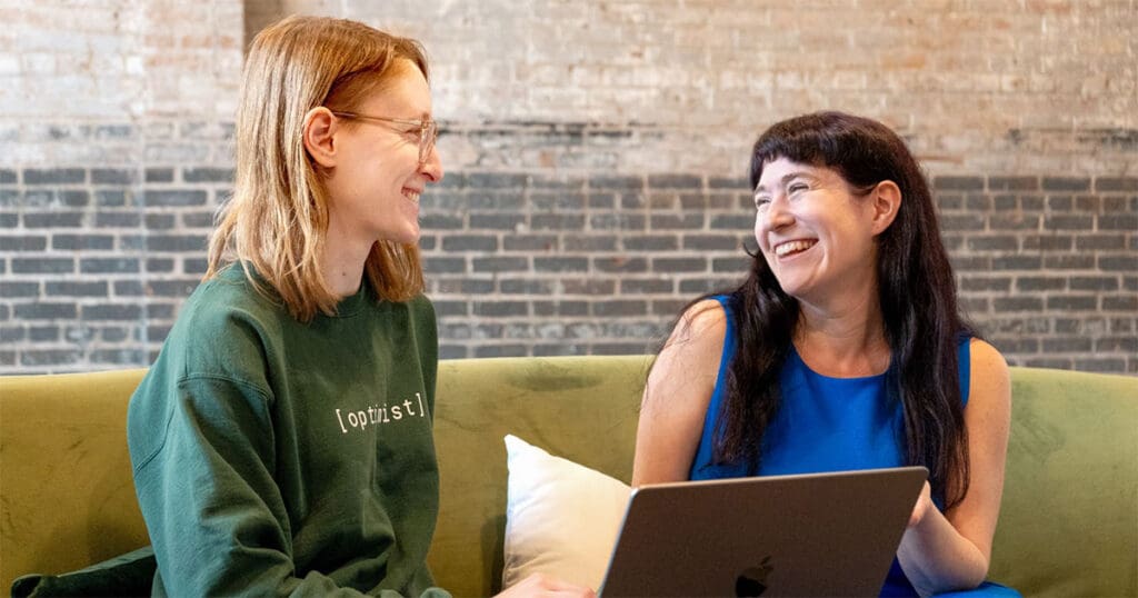 Lauren, our Director of Search and Content, and Simone, our Spring 2025 Content Specialist, smile as they look at a laptop screen.