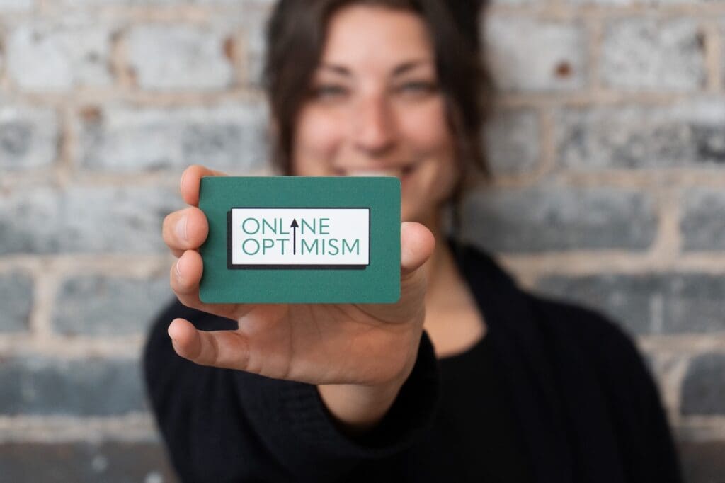 Sara Bandurian holding an Online Optimism business card demonstrating the new logo