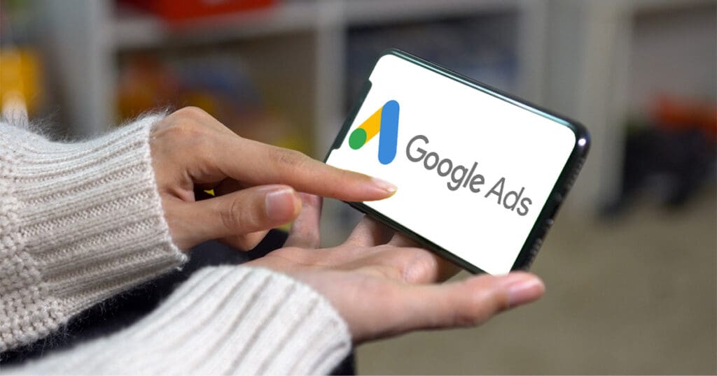 An image of a hand holding a phone with Google Ads written on the screen