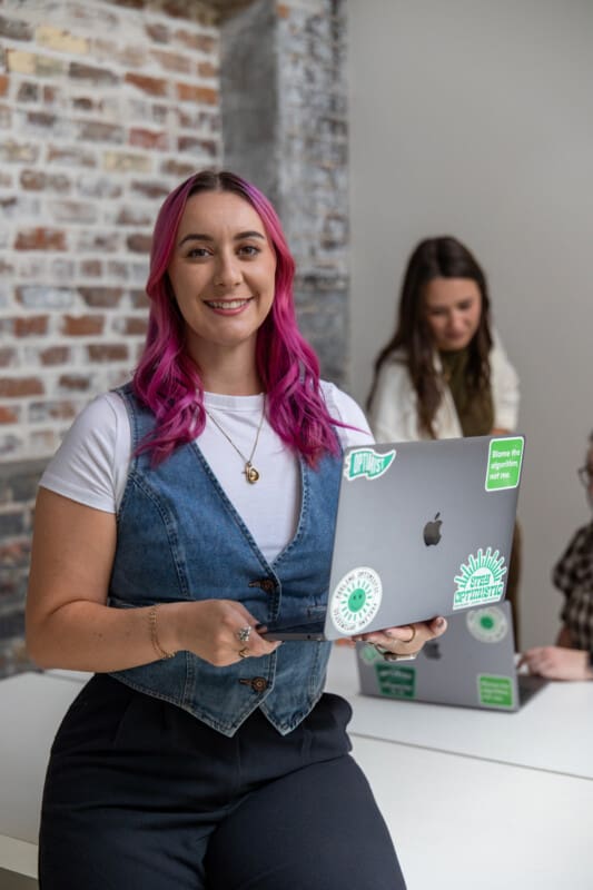 Madison stands with a laptop.