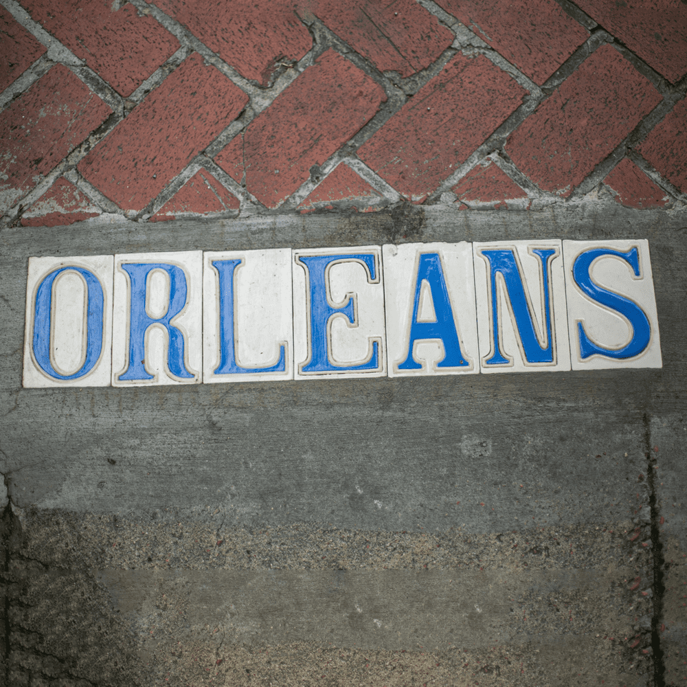 New Orleans blue-letter street tiles on the ground, spelling out "Orleans".