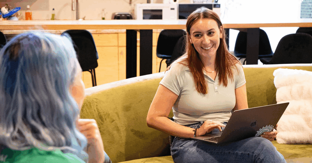 Madison and Meara sit together on the couch at the Online Optimism office, deep in conversation.