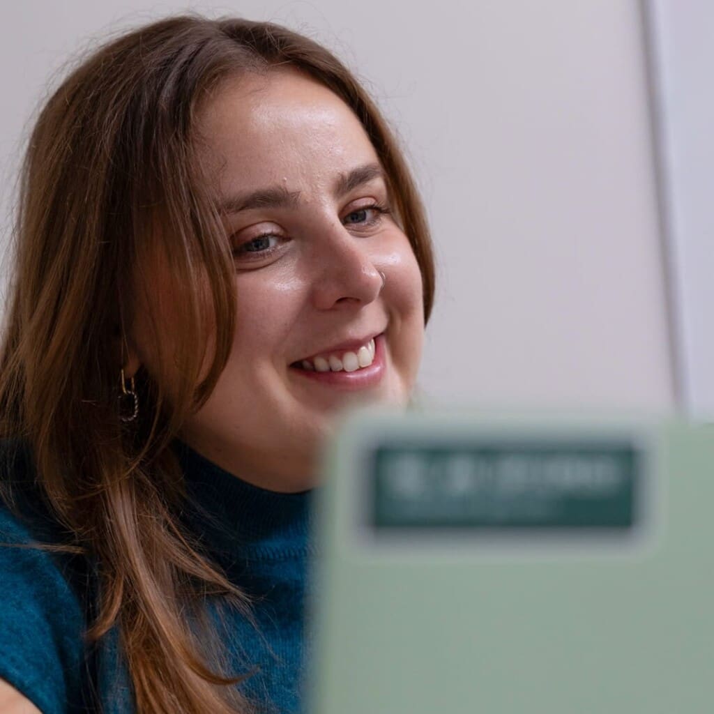 Natasha smiles while working on her laptop