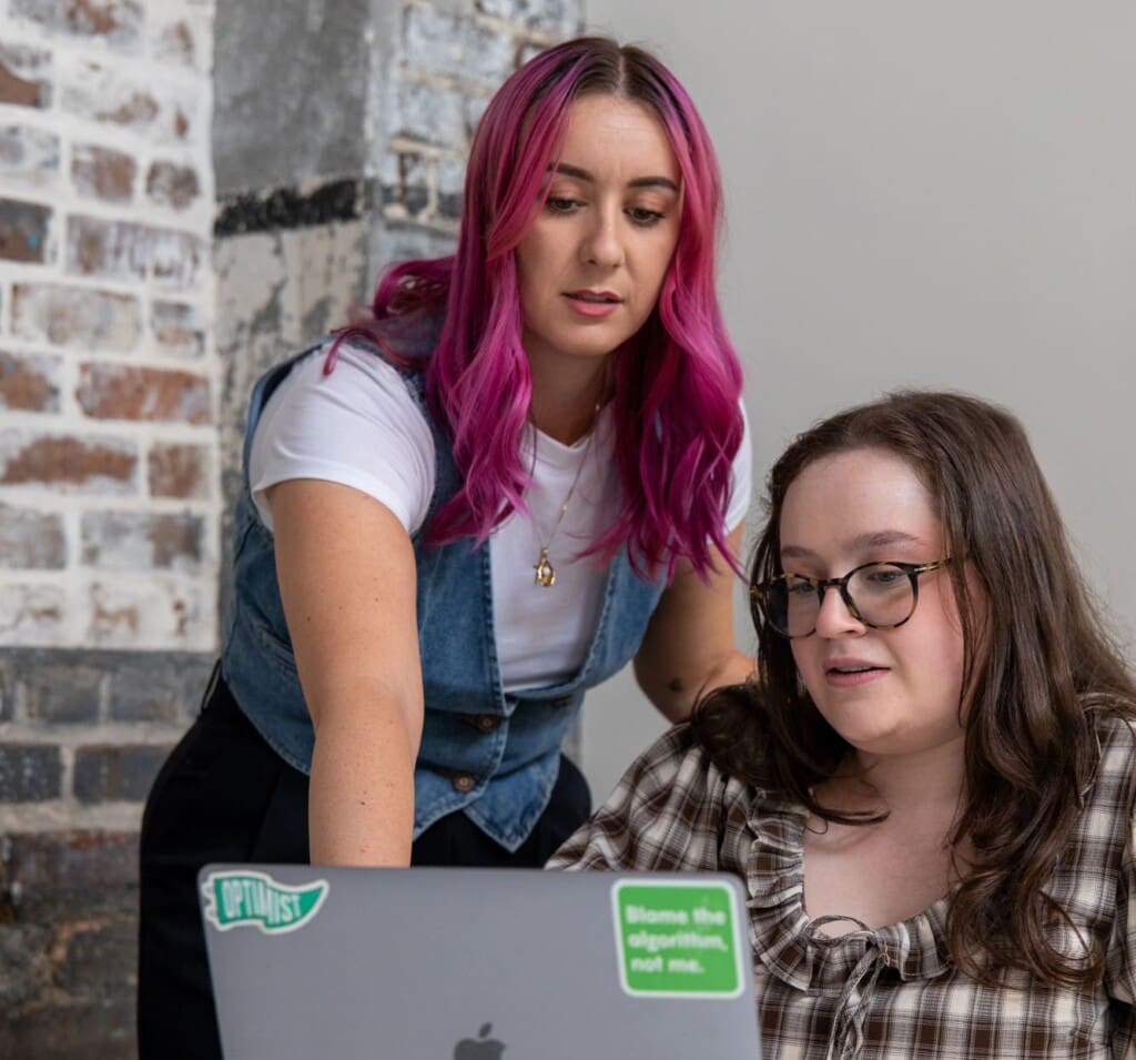 Madison and Abby work together on a laptop.