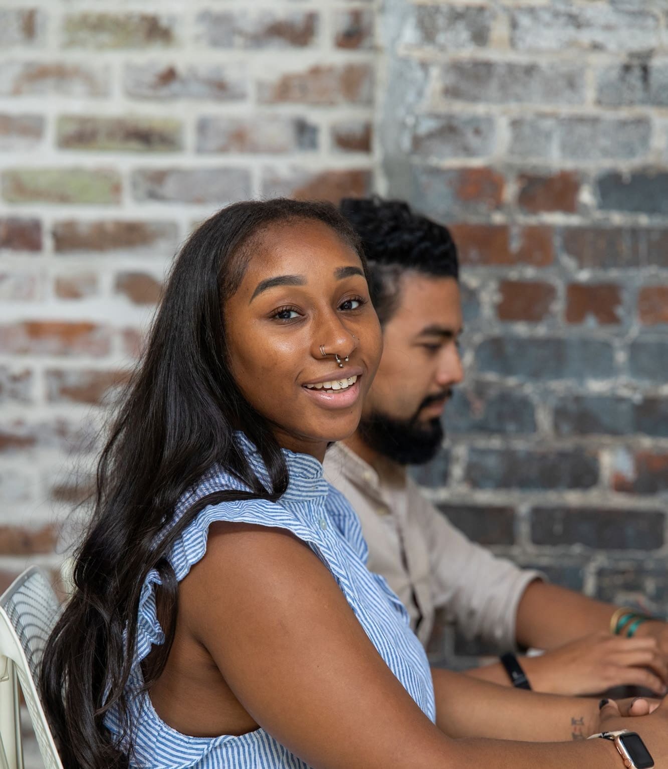 Kimberly looks up to smile while working. Esteban sits next to her.