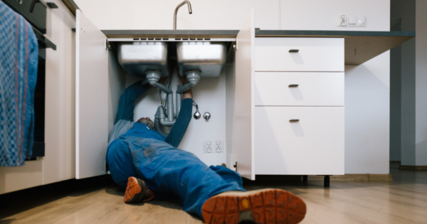 Plumber repairing a kitchen sink during a residential plumbing service call.