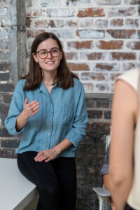 Online optimism design director Claire, sitting on a desk and speaking