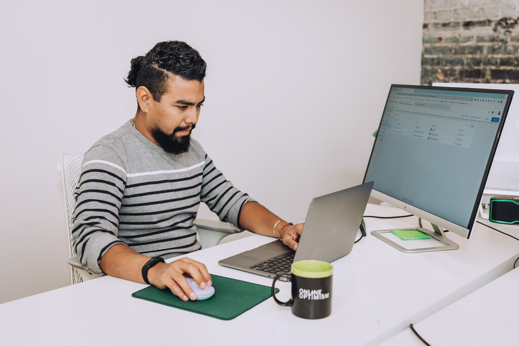 Our Ads Director, Esteban, working from his laptop at the office, with a second monitor and a coffee mug.